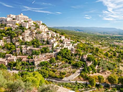 Mittelalterliches Dorf Gordes auf einem felsigen Hang in der Provence, Frankreich. Steingebäude erstrecken sich den Hang hinunter mit Kirche.