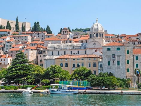 Blick auf die Altstadt von Šibenik vom Wasser aus mit der Jakobskathedrale und ihrer markanten Kuppel, umgeben von historischen Gebäuden.