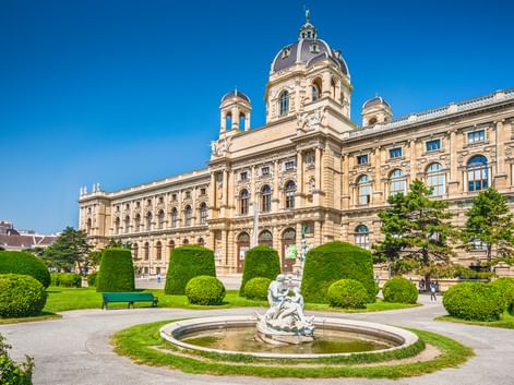 Naturhistorisches Museum Wien mit prachtvoller Barockfassade, zentraler Kuppel und gepflegtem Park mit Brunnen und Formschnitthecken.
