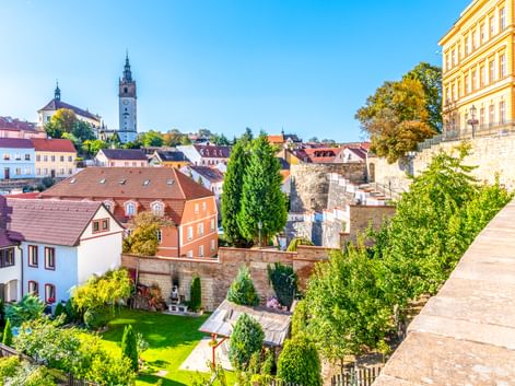Panoramablick auf die Altstadt von Litoměřice mit bunten Gebäuden, Kirchturm und terrassierten Gärten unter blauem Himmel.