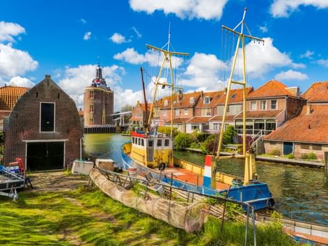 Historischer Hafen von Enkhuizen mit bunten Booten, traditionellen niederländischen Häusern mit orangen Dächern und dem Drommedaris-Turm.