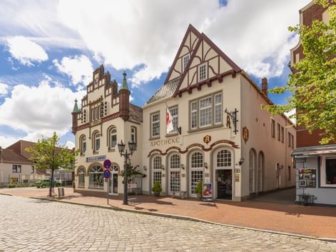 Fachwerkgebäude mit weißer Fassade der Apotheke am Marktplatz in Tönning. Traditionelle deutsche Architektur mit Kopfsteinpflaster unter blauem Himmel.