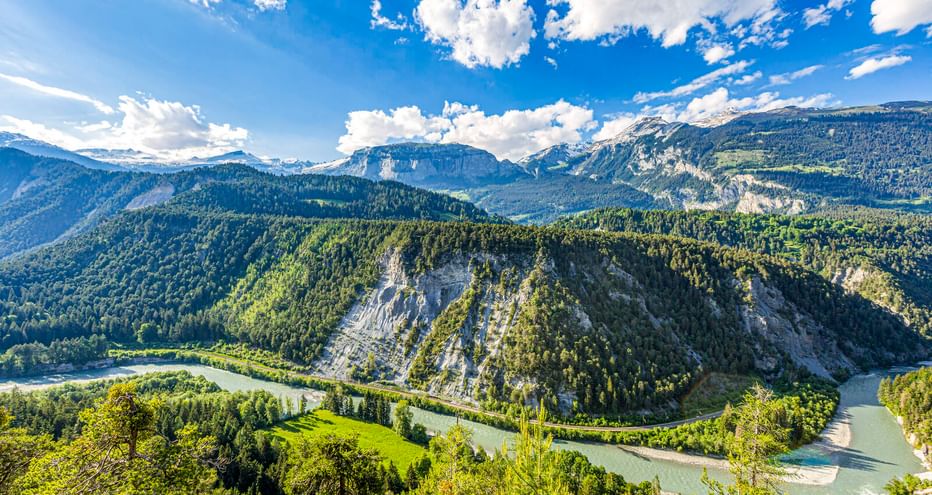 Luftaufnahme der Rheinschlucht in der Schweiz mit türkisfarbenem Fluss, der sich durch bewaldete Berge und weiße Kalksteinfelsen schlängelt.