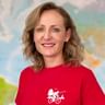 Portrait of Verena wearing a red shirt with cyclist logo, smiling in front of a world map background.